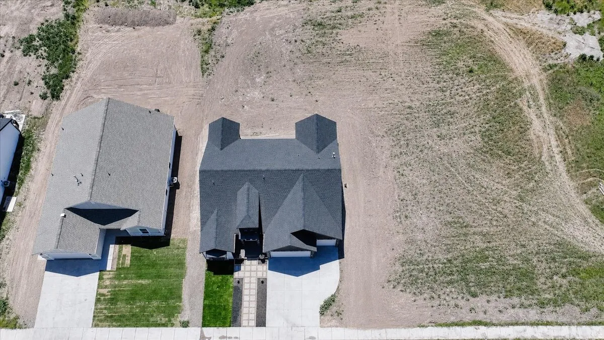 New construction home with a dark gray shingle roof, concrete driveway, and green lawn space