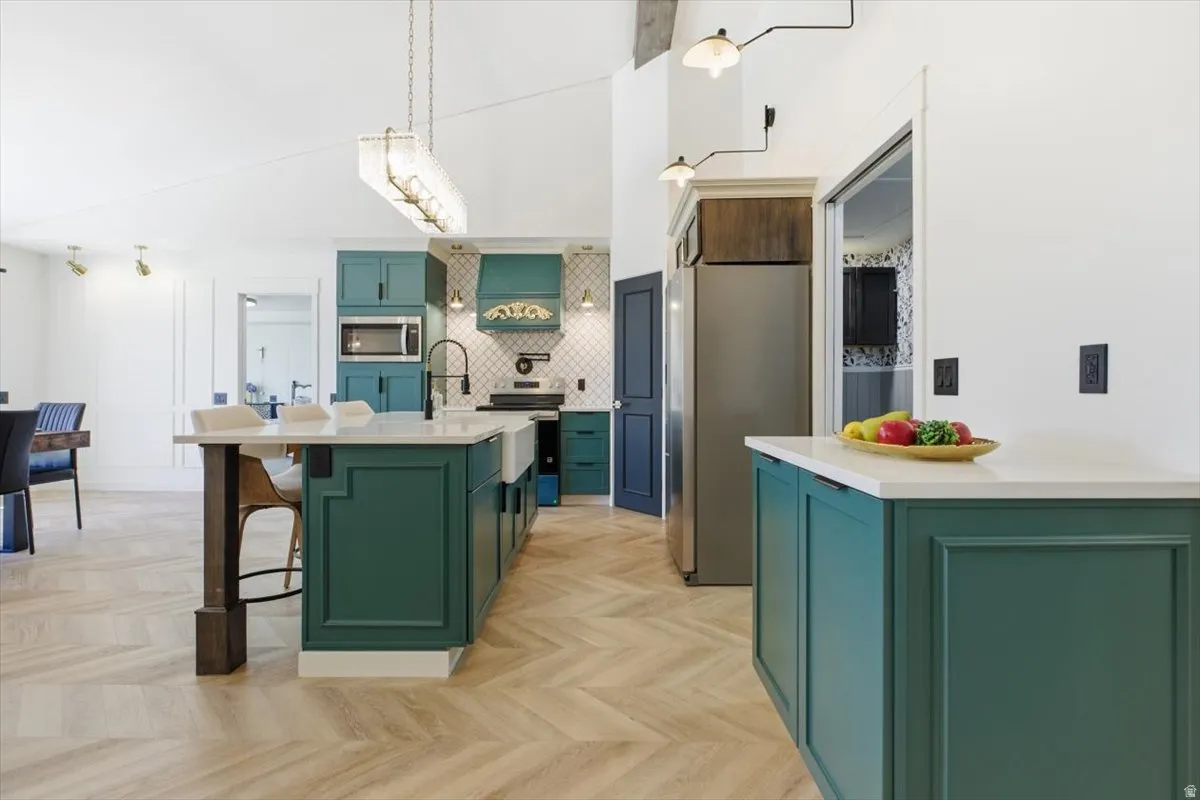 Open-concept kitchen featuring two-tone cabinetry, herringbone wood-finish flooring, a farmhouse sink, stainless steel appliances, and a central island with countertop seating