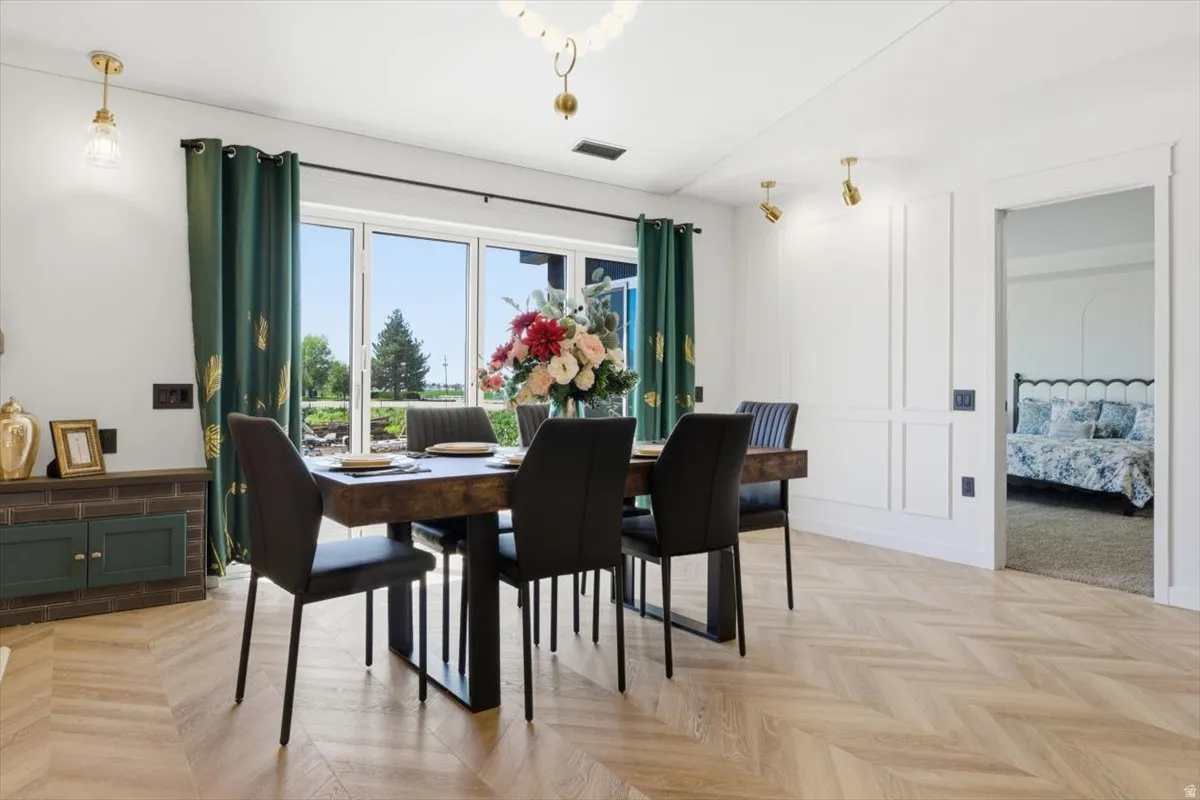 Dining area featuring wood-finish herringbone flooring, a large patio door, built-in wall paneling, and a distinct entryway to an additional room