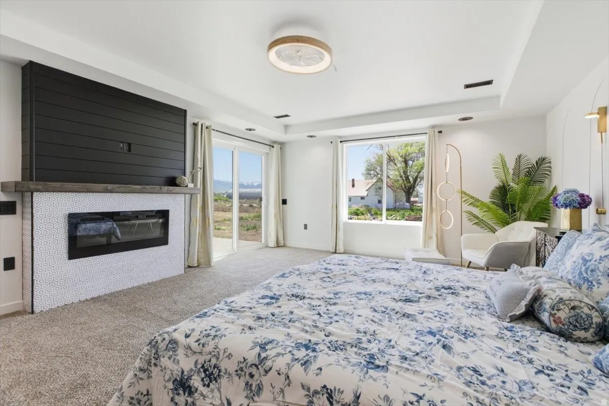 Spacious interior featuring a contemporary fireplace with a shiplap accent wall and a wood mantel, white hexagonal tile surround, carpeted flooring, and a large window with sliding glass door access to the exterior