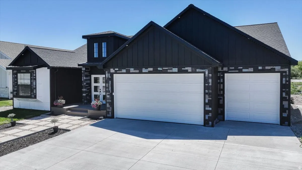 Contemporary exterior featuring dark vertical siding, stone accents, and a threecar garage