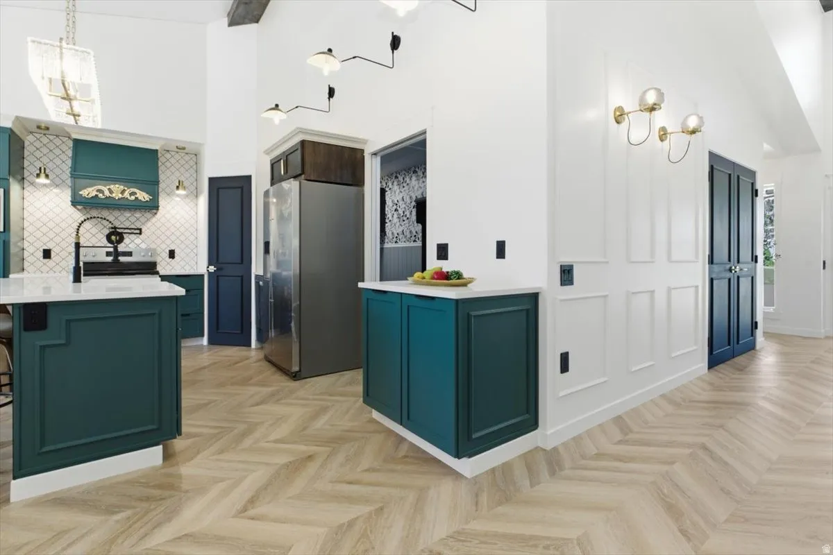 Kitchen featuring dark teal cabinetry, a white diamond-patterned tile backsplash, and light wood-finish herringbone flooring