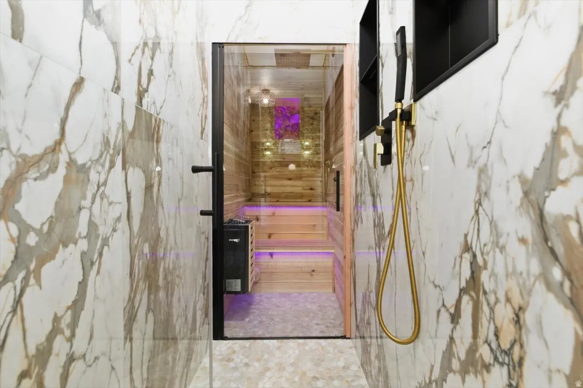 Dedicated sauna room with wood paneling and built-in benches, featuring a glass entry door