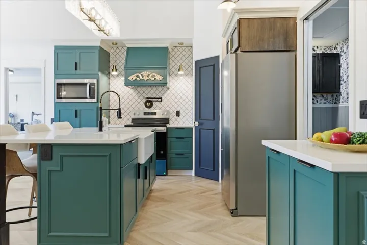 Kitchen featuring a central island with a farmhouse sink, white countertops, and teal cabinetry