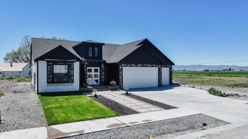 Contemporary facade featuring a black shingle roof, dark vertical siding, white horizontal siding, and stone accents