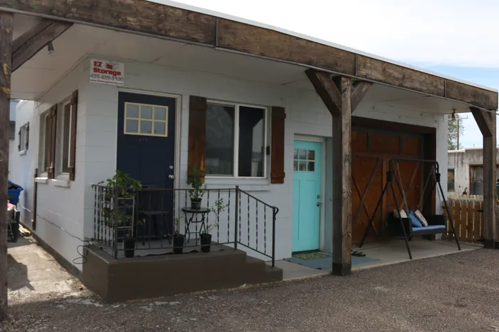 Exterior featuring a white block facade, contrasting dark blue entry door with divided light, and natural wood-toned window shutters