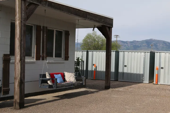 Covered porch with rustic wood posts, featuring a porch swing and a white block exterior