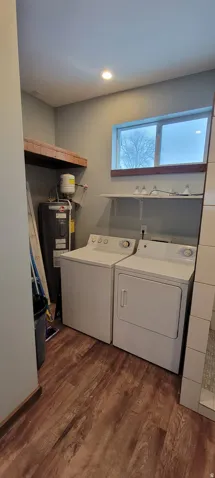 Dedicated laundry area featuring wood-finish flooring, a window with natural light, and a recessed ceiling light