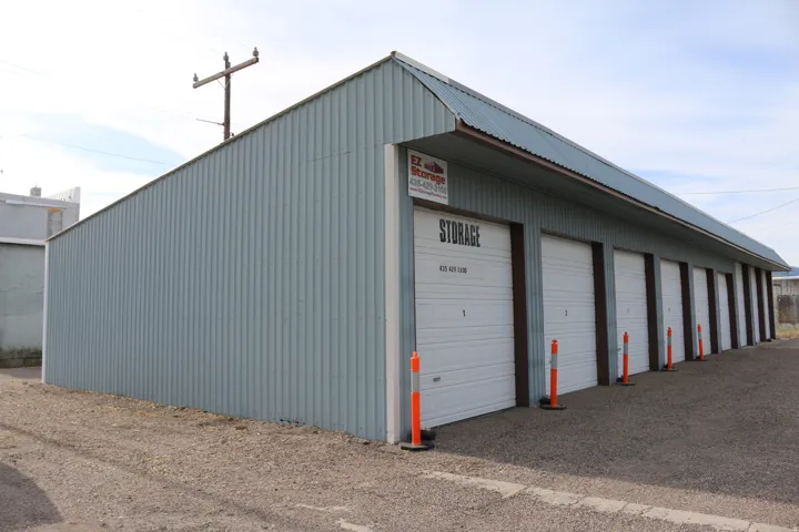 Corrugated metal building featuring multiple white roll-up garage doors BUILT-UNITS 1-9