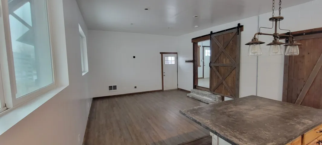 Open-concept living space featuring wood-finish flooring, white walls, and a rustic barn door entry