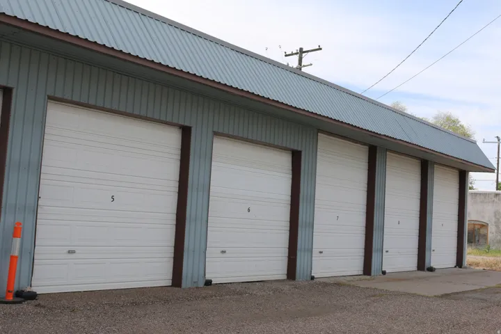 Building exterior featuring multiple bay doors with white paneling, corrugated metal siding, and a corrugated metal roof