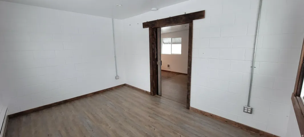 Interior room featuring light wood-finish flooring and white painted cinder block walls