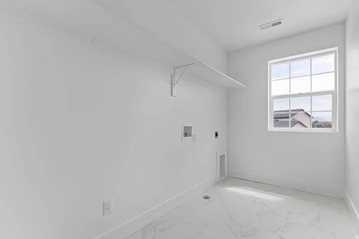 Utility room featuring a grid-pattern window, white wall shelving, and a bright white color palette