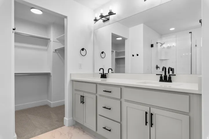 Dual vanity with light-toned cabinetry and countertops, featuring matte black fixtures and hardware
