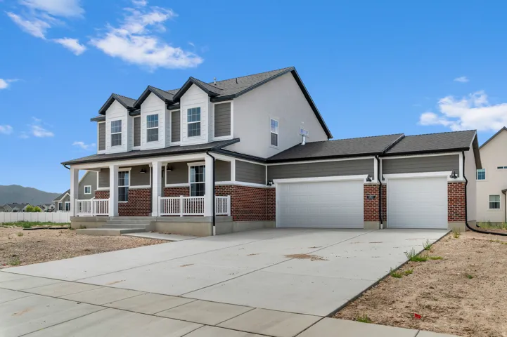 Two-story residence featuring a covered front porch with white railings, a three-car garage, and a concrete driveway