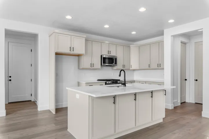 Kitchen featuring light-toned cabinetry, a central island with countertop space, and wood-finish flooring