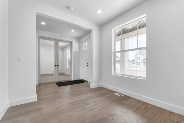 Bright interior space featuring wood-finish flooring, recessed lighting, and a large window with grid panes