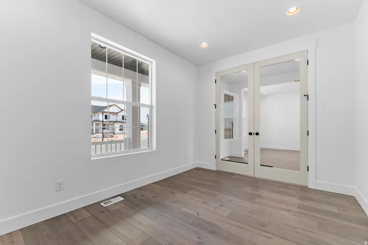Room featuring wood-finish flooring, crisp white walls, and recessed lighting