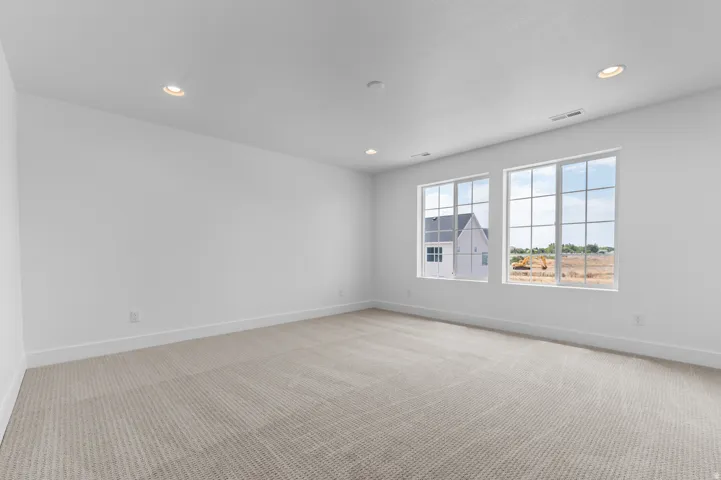 Bright interior space featuring two large grid-pattern windows, recessed lighting, white walls, and a light-toned carpet