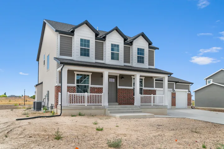 Two-story residence featuring a covered front porch with white railing, brick accents, and a two-car garage