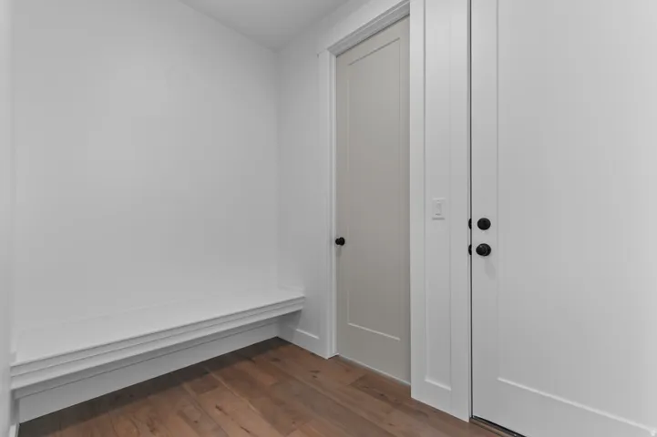 Entryway featuring a built-in bench, wood-finish flooring, two panel doors, and matte black hardware