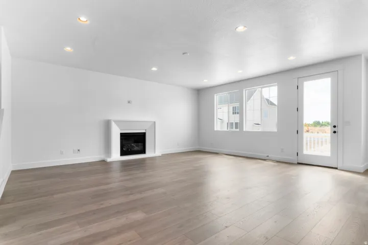 Spacious room featuring wood-finish flooring, a contemporary fireplace, recessed lighting, and white trim