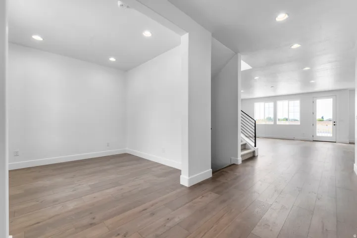 Open-concept living space featuring wood-finish flooring, recessed lighting, white baseboards, and white walls