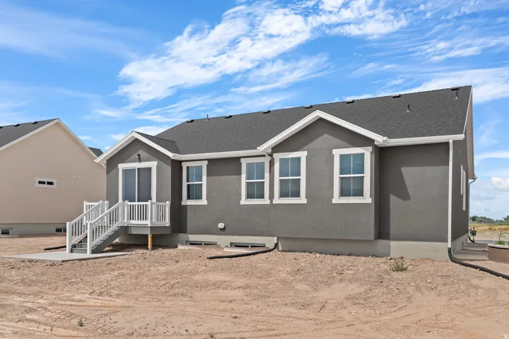 Rear exterior featuring a gray stucco finish and a dark shingle roof