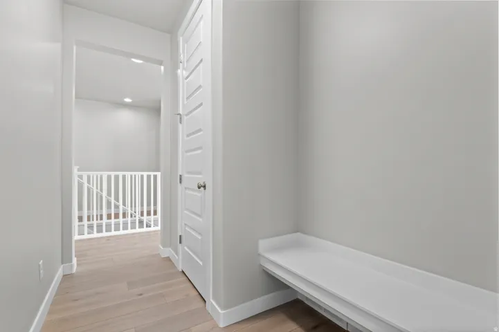 Hallway featuring light wood-finish flooring, white baseboards, and a built-in white bench