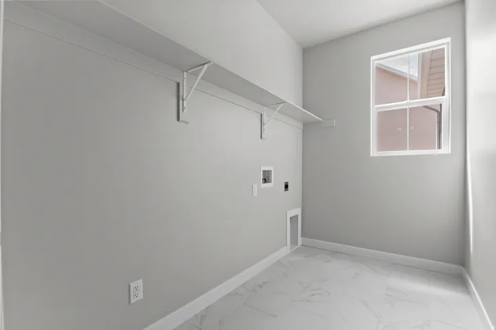 Utility room featuring a window, built-in shelving, appliance connections, and light-toned tile flooring