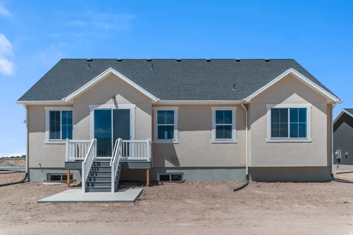 Rear elevation featuring a sliding glass door and deck with white railings