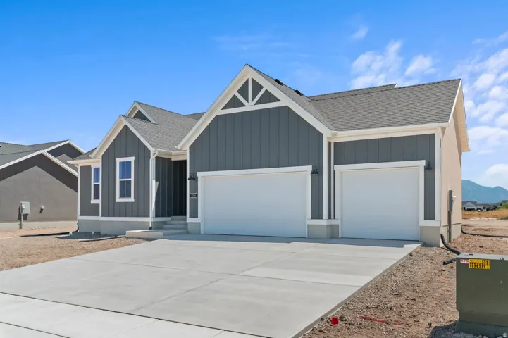 Contemporary ranch-style home featuring gray vertical siding, white trim accents, a concrete driveway, and a two-car garage