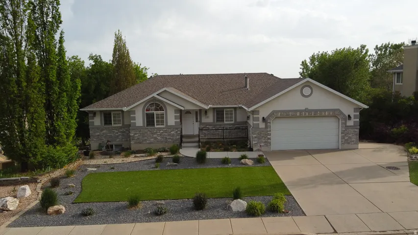 Ranch-style residence featuring a stone and stucco facade, a two-car garage, and an arched transom window above the main entry