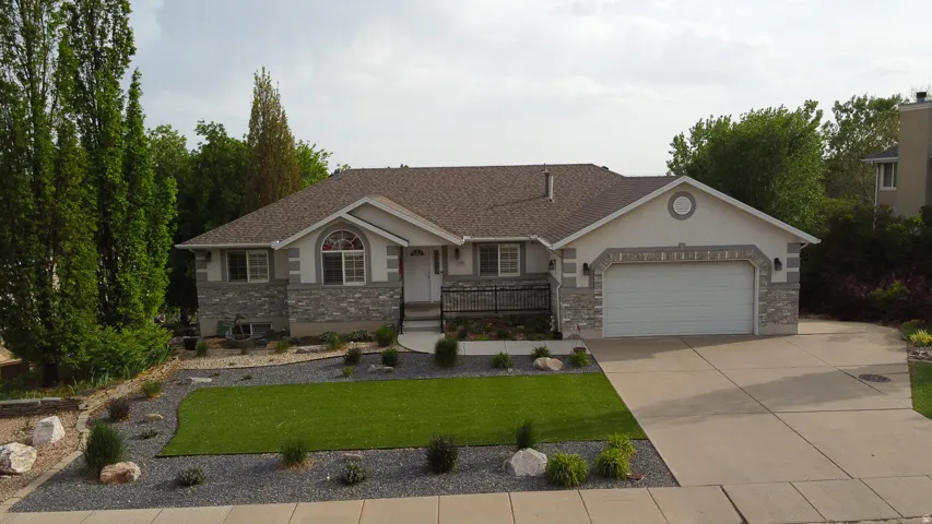 Single-story residence featuring a two-car garage, stone and stucco exterior, and a paved driveway