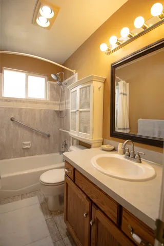 Bathroom featuring a wood-finish vanity with a light-toned countertop and an oval sink