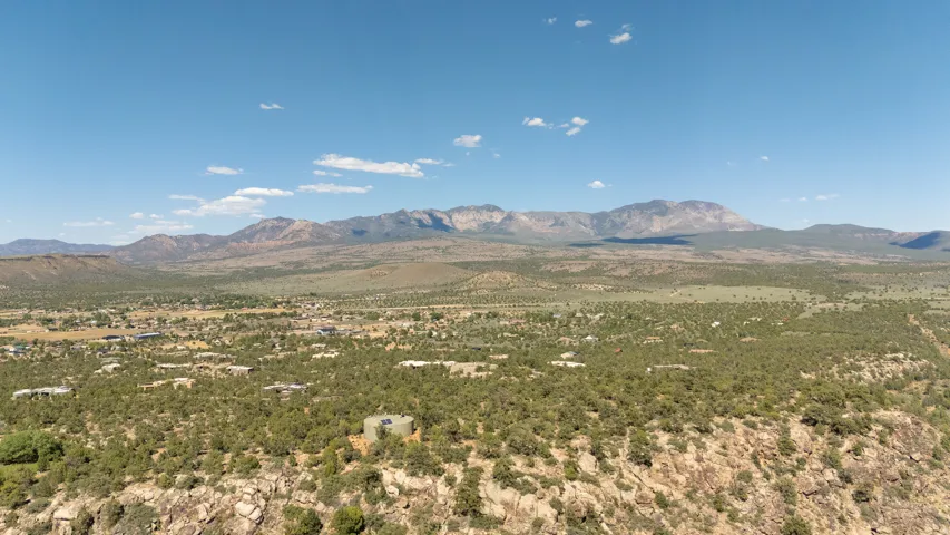 Expansive landscape featuring distant mountains, a valley with scattered residential structures, and abundant green foliage