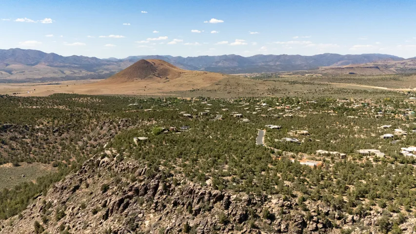Expansive landscape with a prominent volcanic cone, surrounded by rolling hills and scattered residential properties