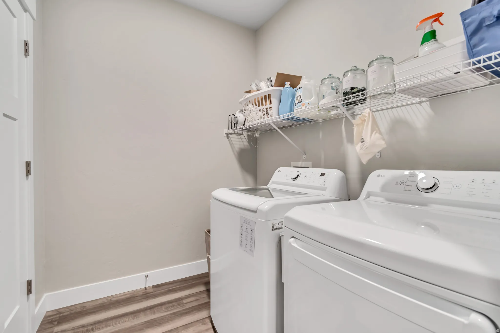 Dedicated laundry area featuring wood-finish flooring, light grey wall paint, and white baseboards