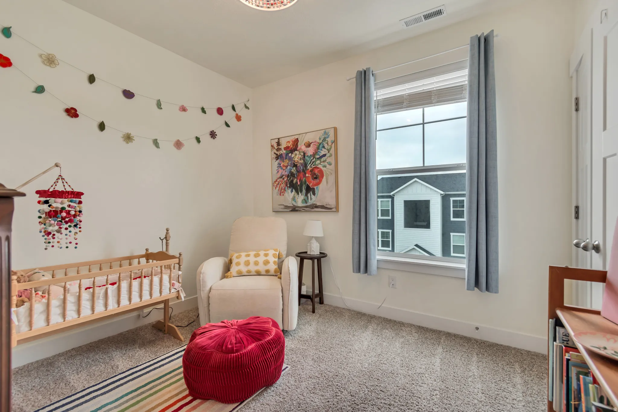 Bright room featuring light-colored walls, a large window with blinds, and neutral carpet flooring