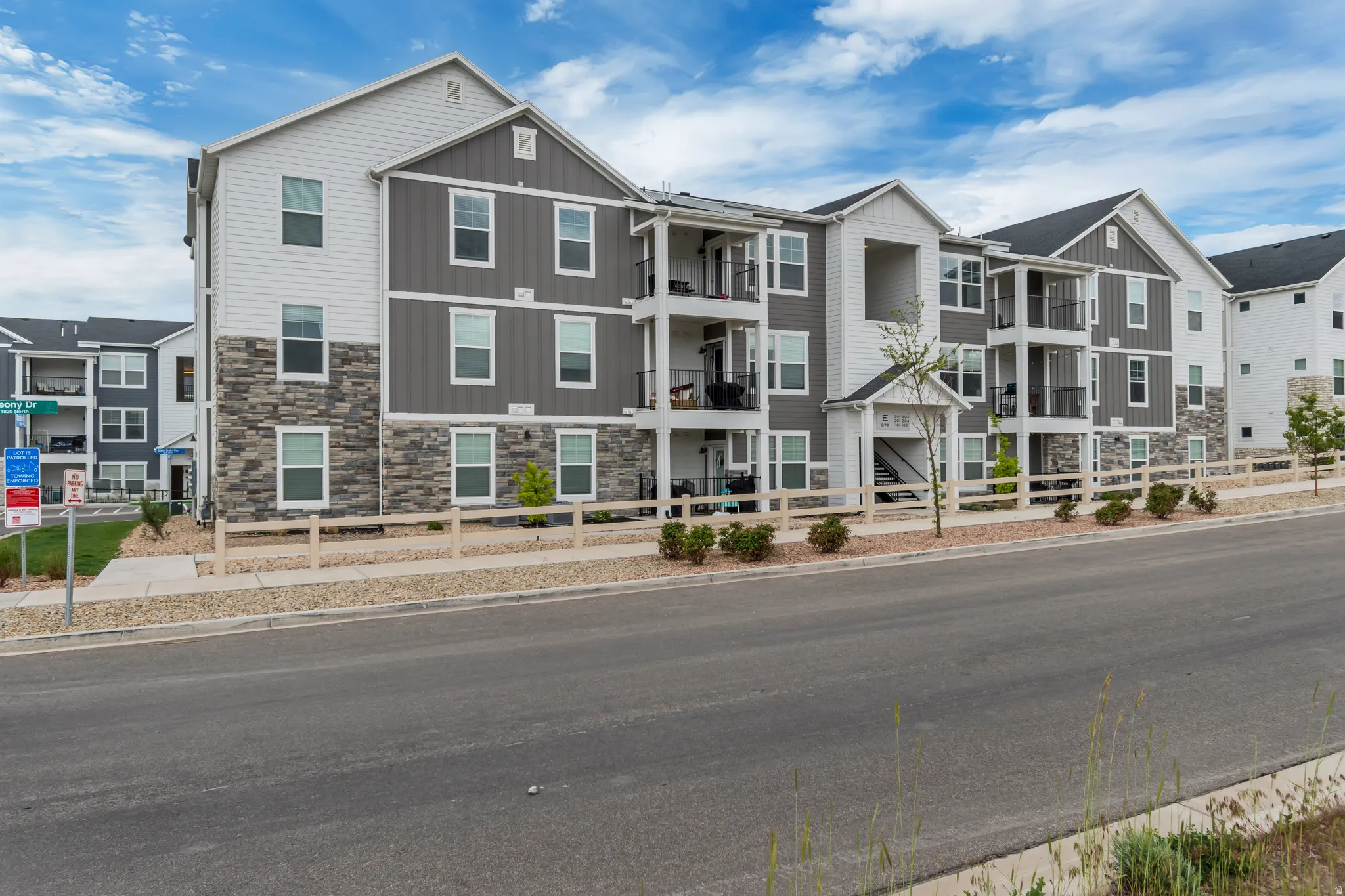 Multi-story exterior featuring white and gray siding with stone veneer accents