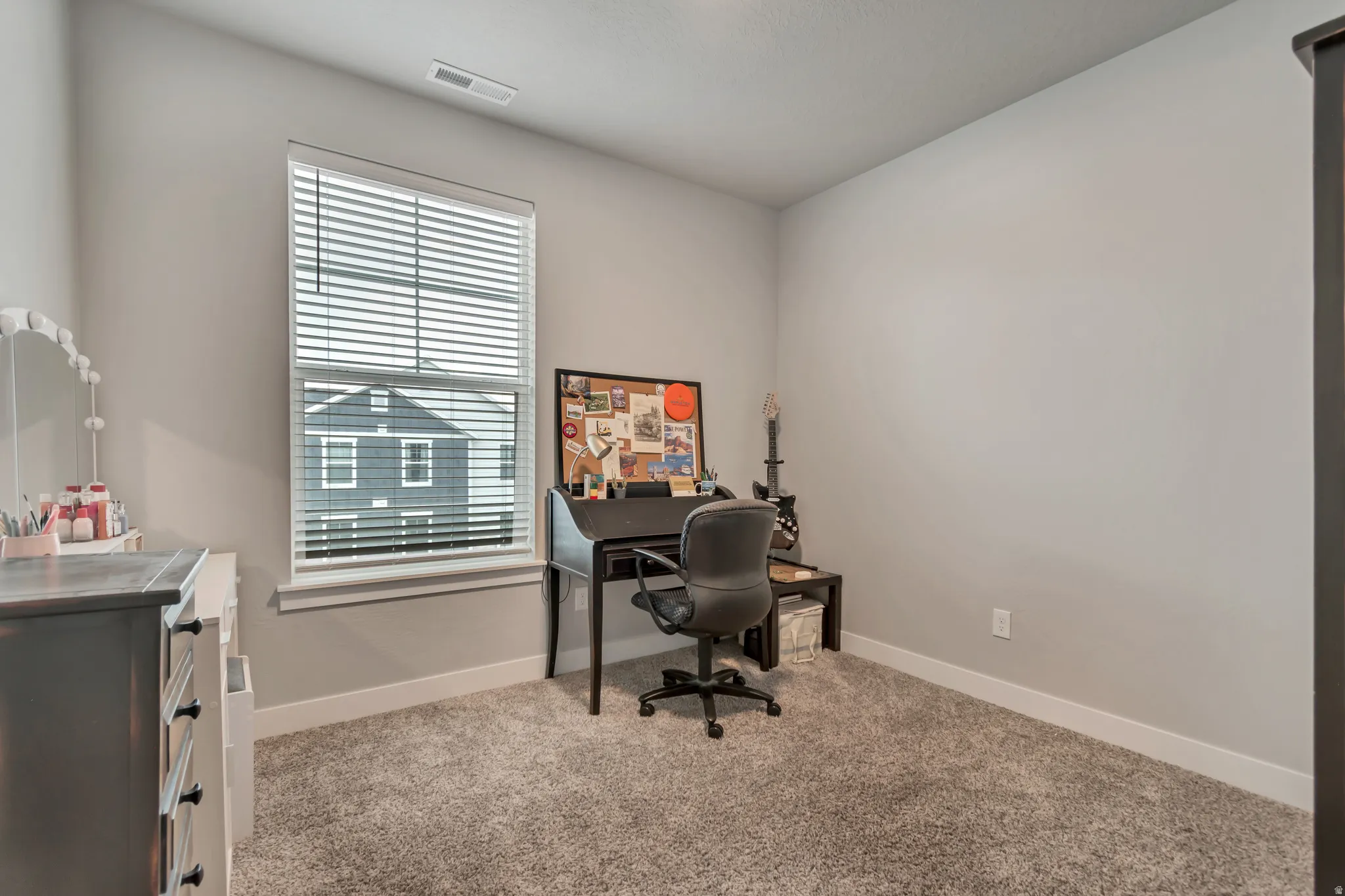 Bright room featuring a single window with blinds, light-toned walls, white baseboards, and neutral carpeting