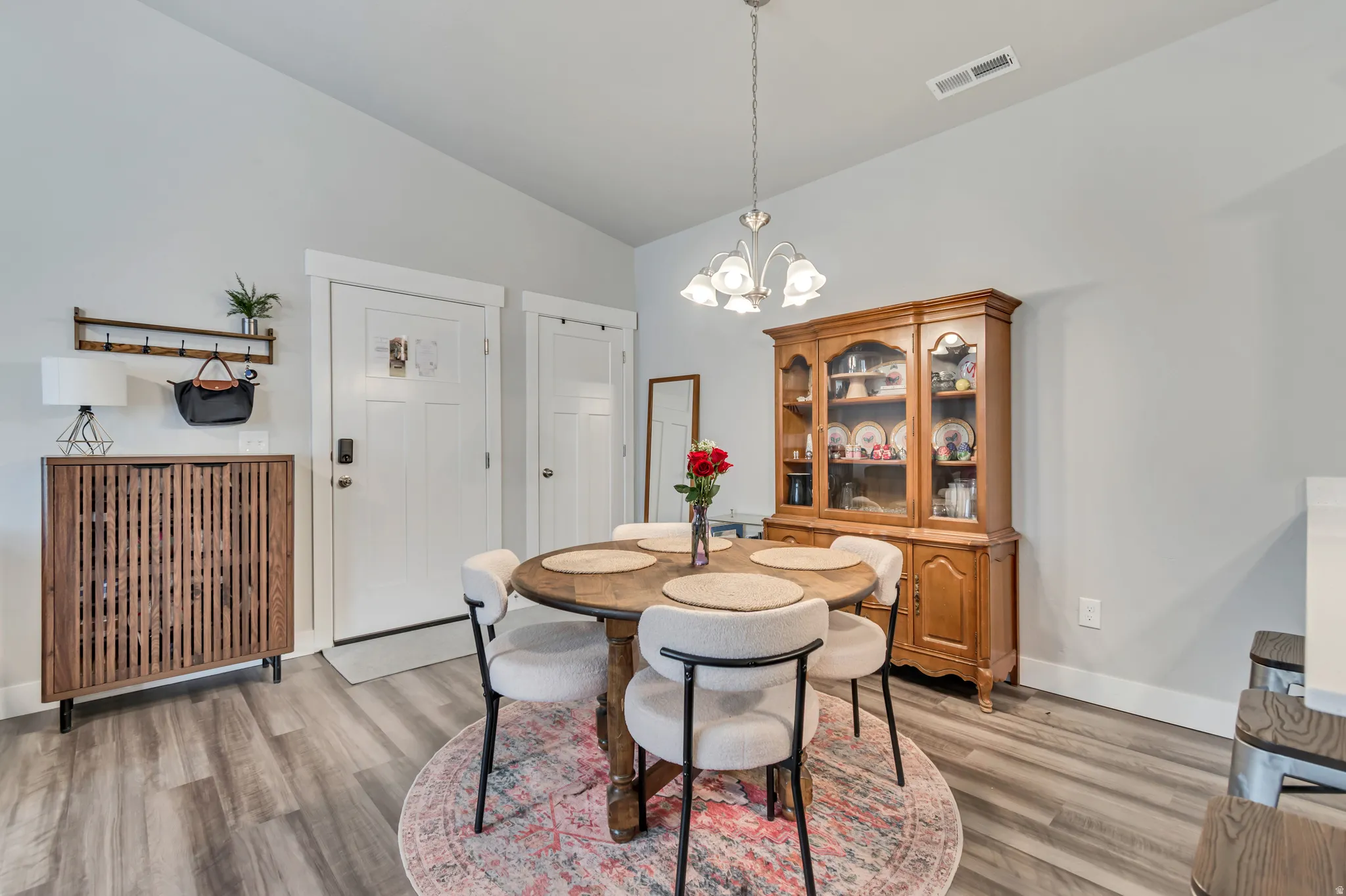 Spacious dining area featuring wood-finish flooring, a traditional chandelier, and light gray wall paint