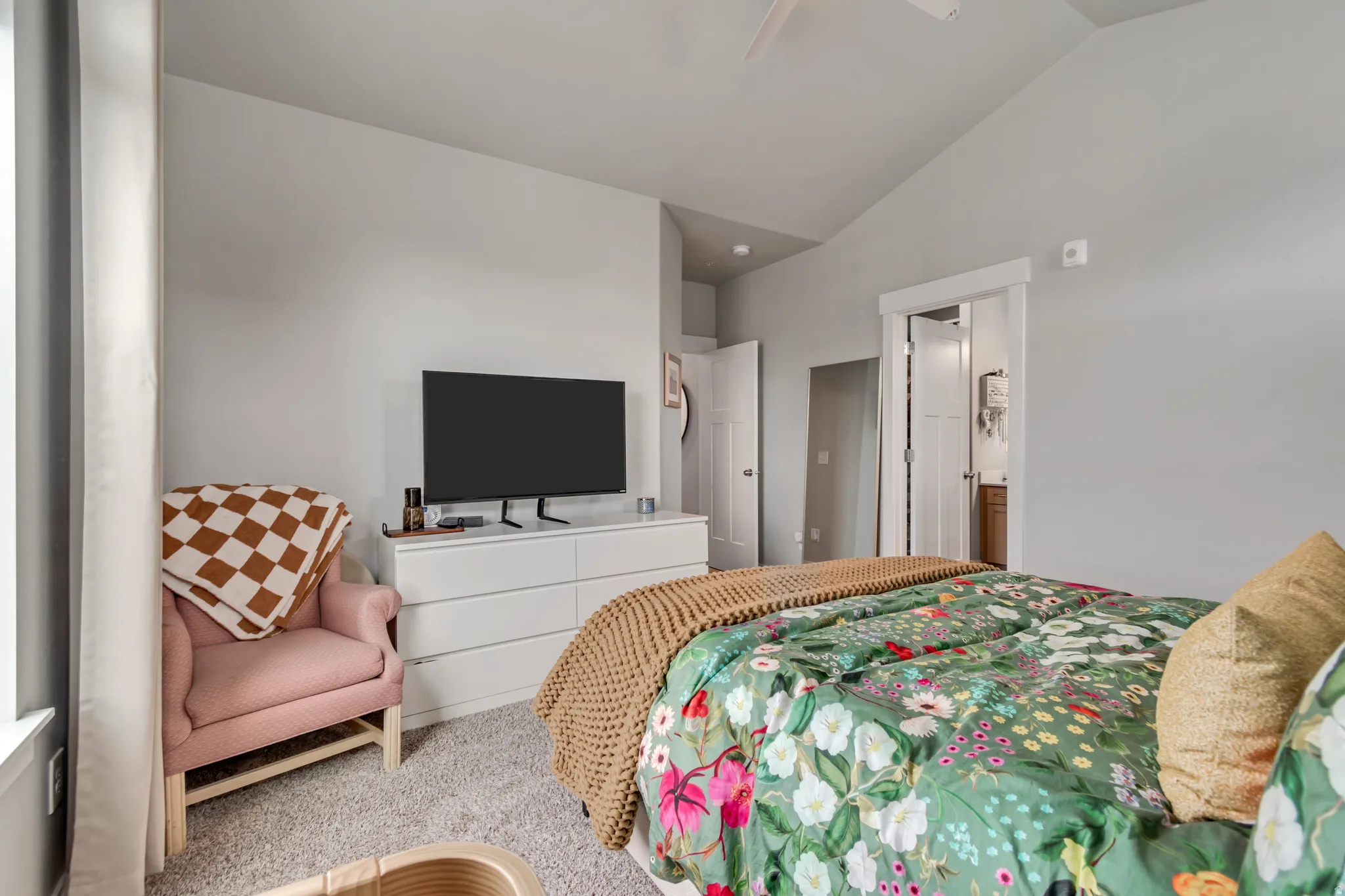 Vaulted ceilings enhance this carpeted room, featuring light gray walls and white trim