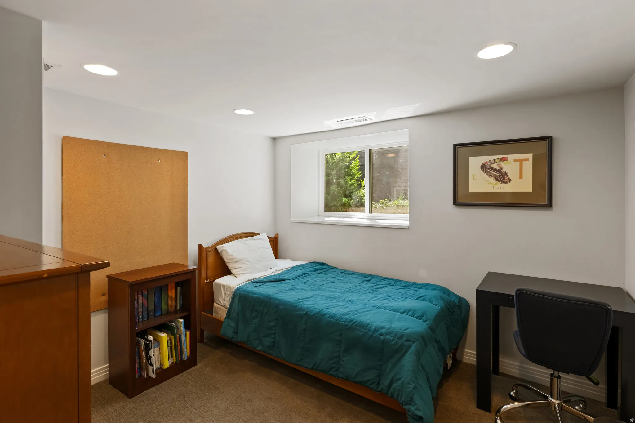 Well-lit room featuring recessed ceiling lighting, a window with exterior views, light gray wall paint, white baseboards, and carpeted flooring