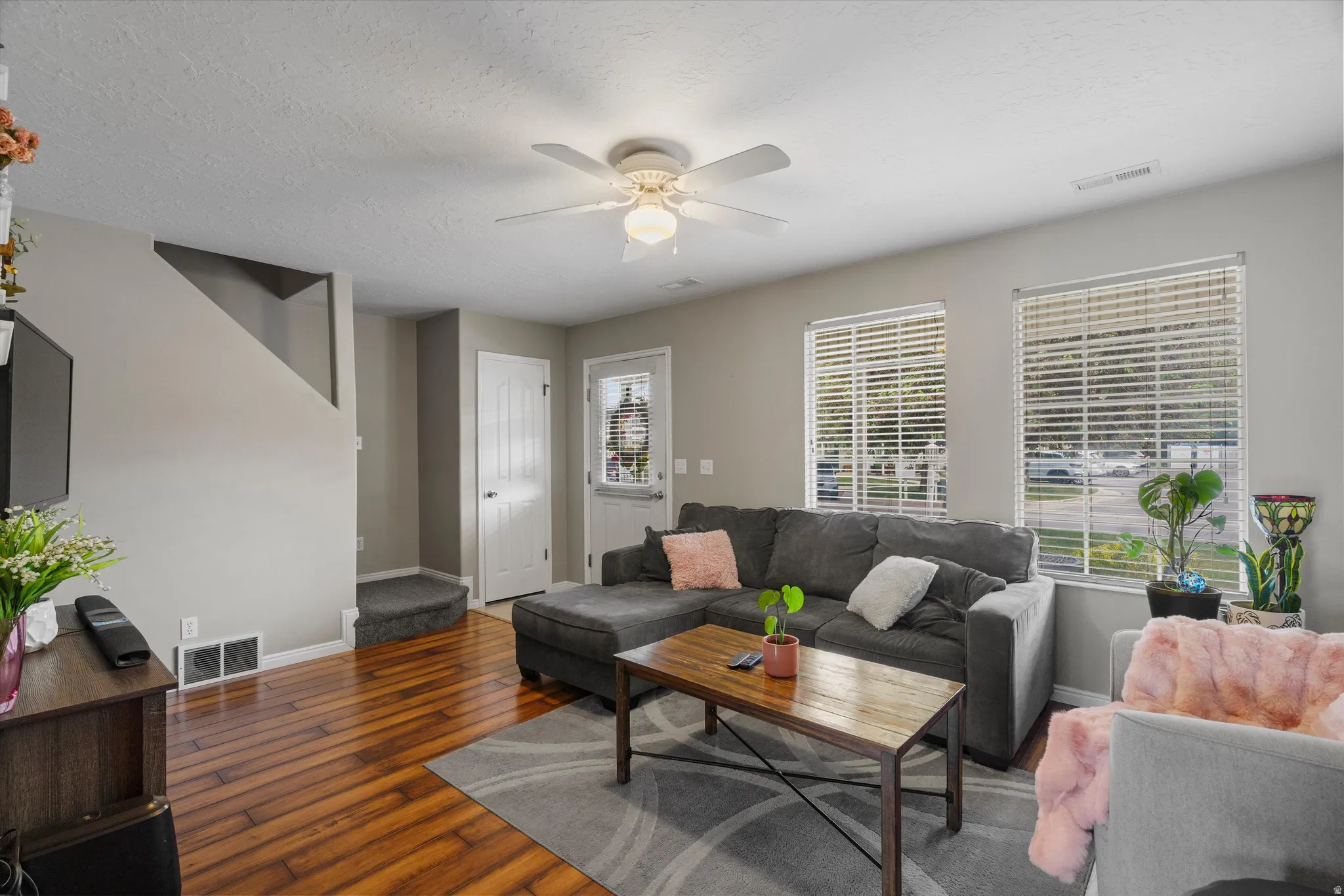 Spacious living area featuring laminate flooring, light gray wall paint, and a ceiling fan with integrated lighting