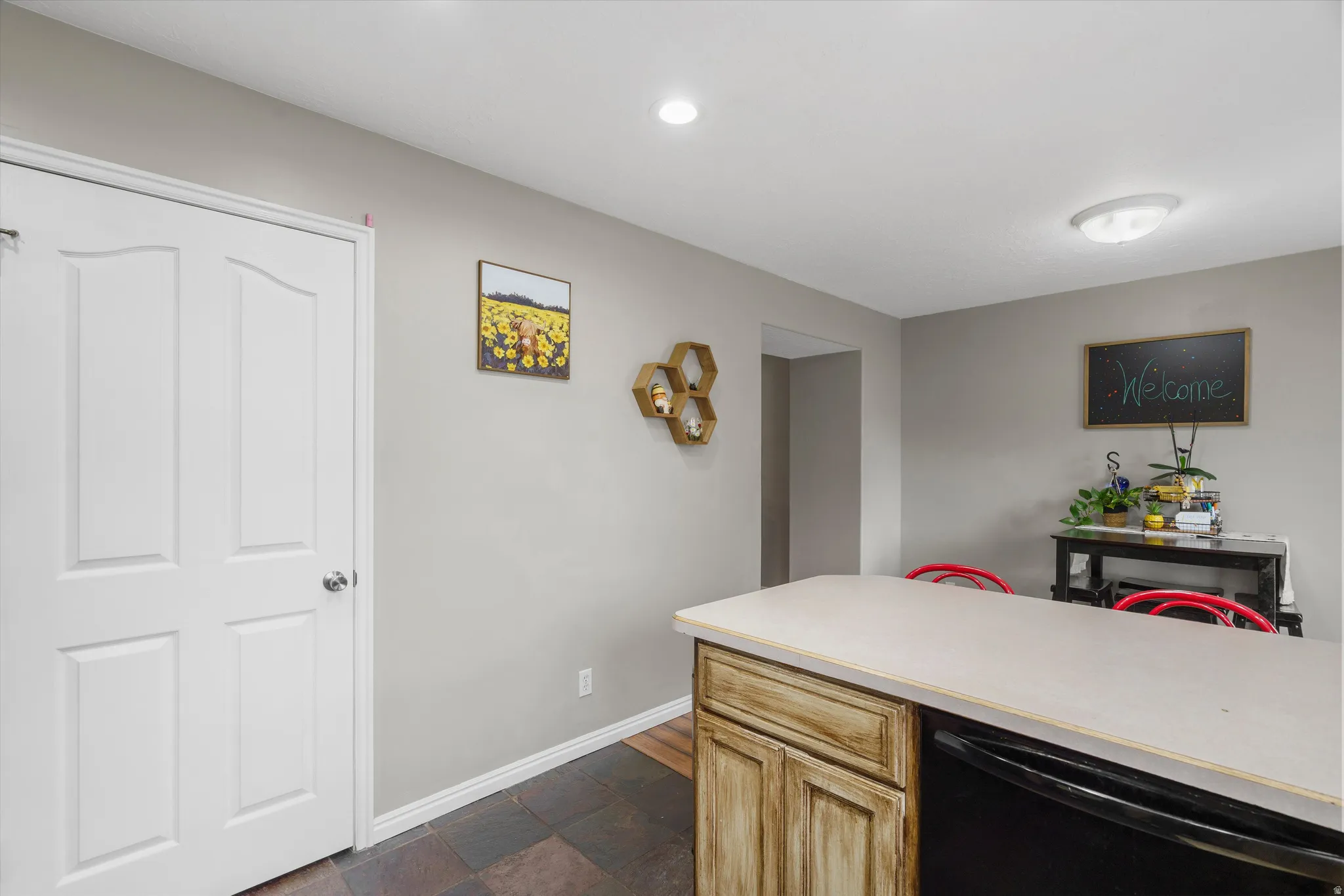 Kitchen island with light-toned countertop, wood-finish cabinetry, and integrated black appliance
