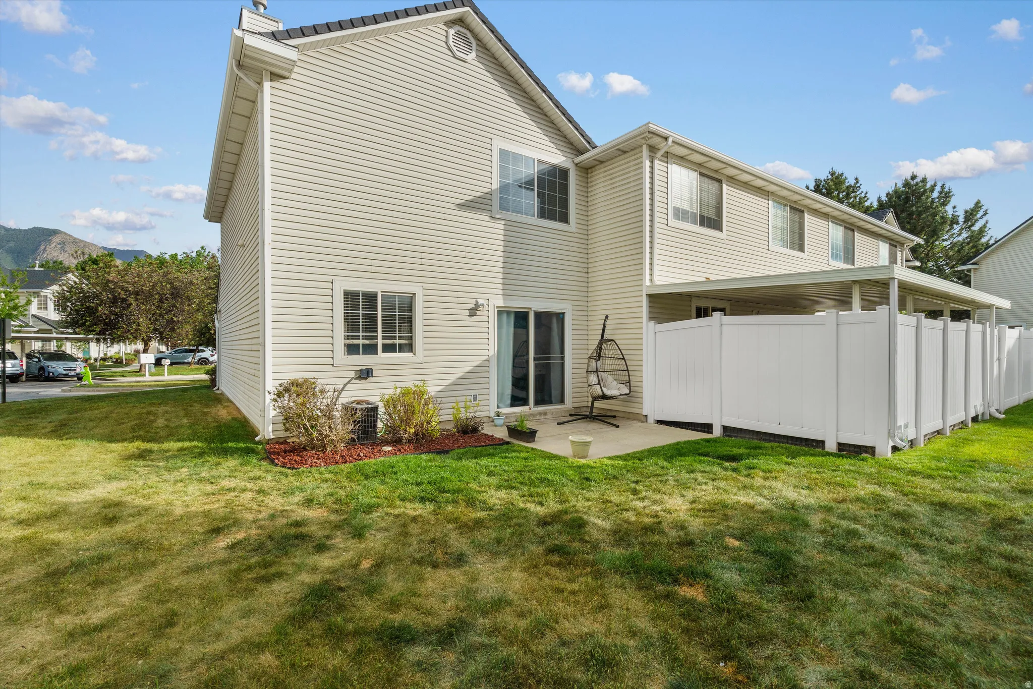 Rear exterior featuring light-colored siding, multiple windows, and a sliding glass door