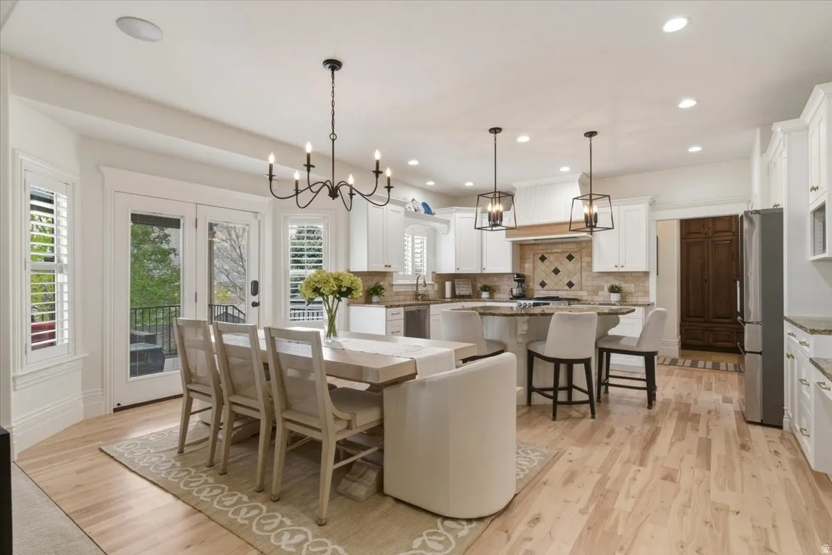 Open-concept kitchen and dining area featuring light wood-finish flooring, white cabinetry, and granite countertops