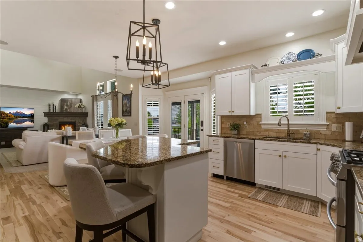 Expansive kitchen featuring a large island with seating, stainless steel appliances, and light wood-finish flooring