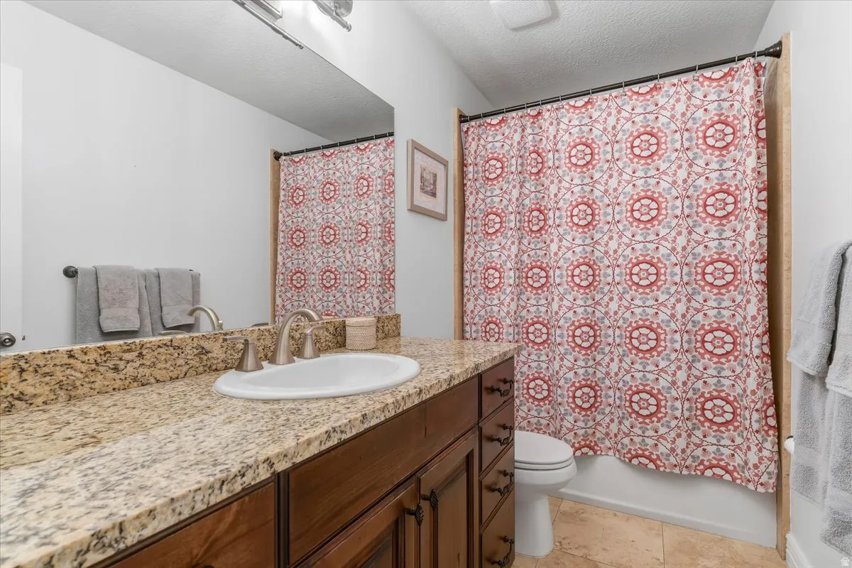 Bathroom featuring a single-sink vanity with a granite countertop, wood-finish cabinetry, and a brushed nickel faucet